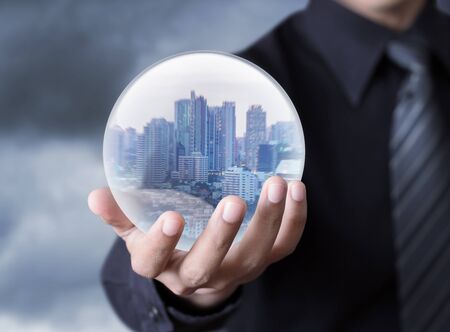 Business man holding a city inside a sphere, City of the futureの写真素材