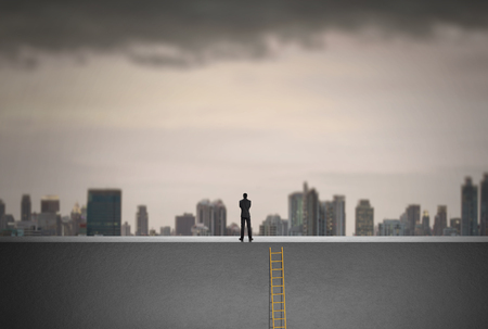 Businessman climbing on a ladder over a city looking ahead, Leadership conceptの写真素材