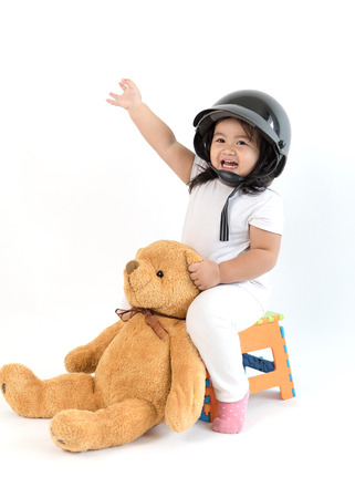 child wearing helmet and playing a ride with teddy bearの写真素材