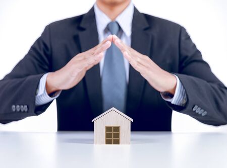 businessman covering home with hands, insurance conceptの写真素材