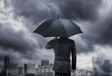 businessman hold umbrella under rain storm with city   backgroundの写真素材