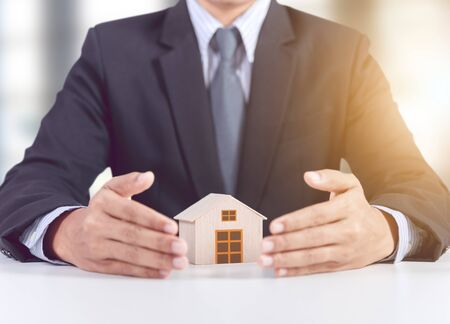 businessman hand cover wooden home model, insurance conceptの写真素材