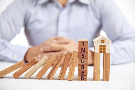 businessman and wooden domino with word insured, insurance conceptの写真素材