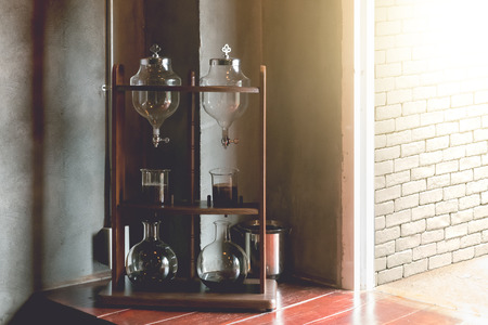 Lab tube and equipment on wooden table with brick wall background, cold brew coffee