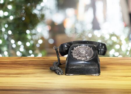 black old vintage telephone on wooden brown table with night bokeh backgroundの写真素材