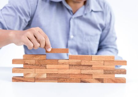 businessman hand put wooden toy block, developmentの写真素材