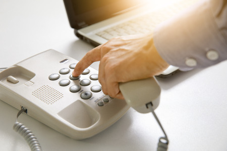 businessman dial digital telephone with office backgroundの写真素材