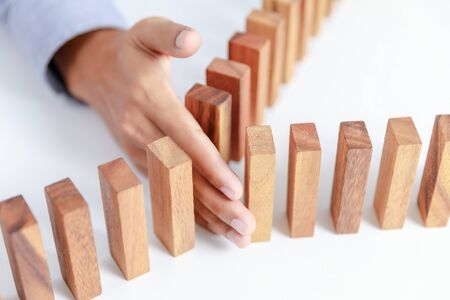 businessman hand project wooden toy block from danger and fall, insuranceの写真素材