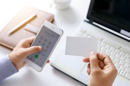 businessman hold blank paper card on hand with office desk backgroundの写真素材