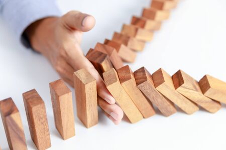 businessman hand protect wooden toy block from danger and fall, insuranceの写真素材