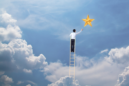businessman climb up on ladder to reach star, successful and win conceptの写真素材