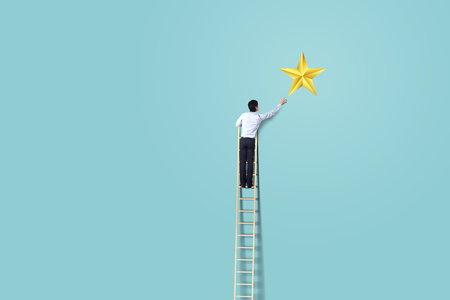 businessman climb up on ladder to reach star, successful and win conceptの写真素材