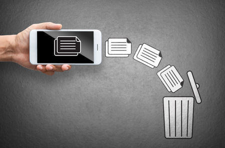 business hand throw data file from mobile to trash binの写真素材