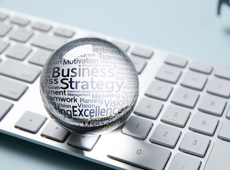 Business icon in crystal ball on white computer keyboardの写真素材