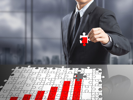 Businessman present missing jigsaw with growing rising graphの写真素材