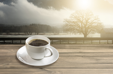 Hot americano black coffee in white mug with sunrise mountainの写真素材