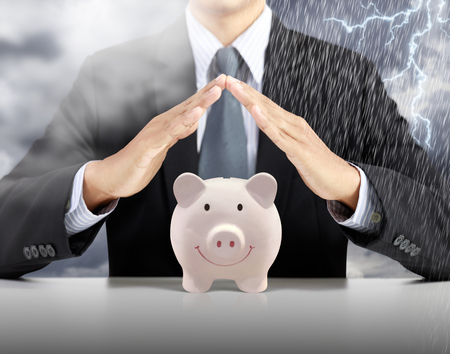 Businessman hand cover pink piggy ceramic bank with heavy rain stormの写真素材