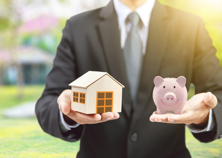 Pink piggy ceramic bank and home model with businessman, insurance conceptの写真素材