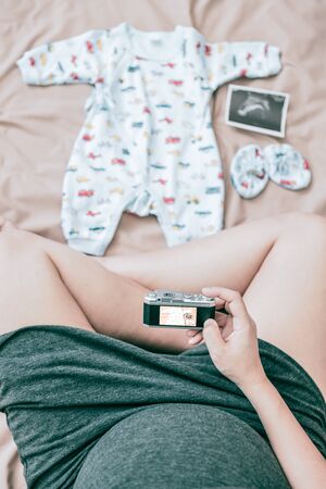 Pregnant woman with ultrasound image of baby in belly, medical technology