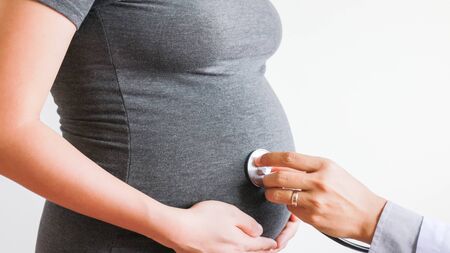 Pregnant woman listen to baby heart beat with doctor stethoscopeの写真素材