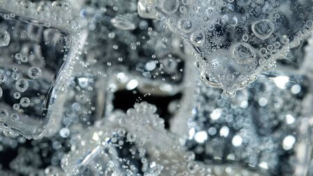 Ice cube in fizzy splashing water with soda bubbleの写真素材