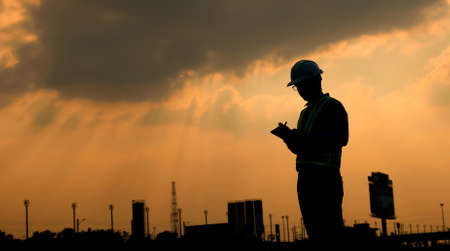 Engineer use digital tablet at construction site, in sunset silhouette