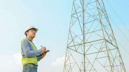 electrical engineer working on digital tablet with electric power pole backgroundの写真素材