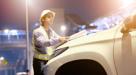 engineer look at blueprint draft paper in car at construction siteの写真素材