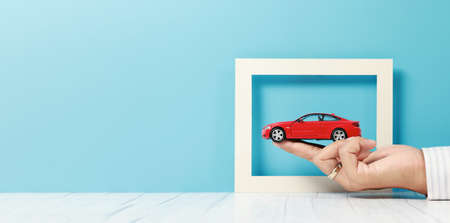 businessman hand holding a car model, insurance conceptの写真素材