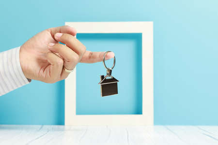 businessman hand holding house key chain, real estate and propertyの写真素材