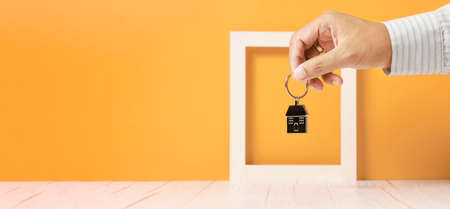 businessman hand holding house key chain, real estate and propertyの写真素材