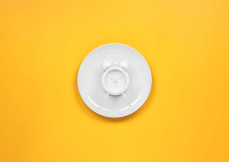 alarm clock on a dish with fork and knifeの写真素材