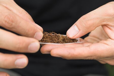 photo showing hands of a male rolling tobbaccoの写真素材
