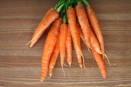 bunch of organic carrots placed on wooden surfaceの写真素材