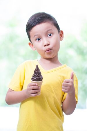 Happy asian boy eating chocolate ice-cream.の写真素材
