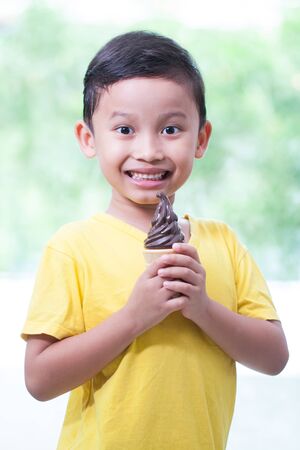 Happy asian boy eating chocolate ice-cream.の写真素材