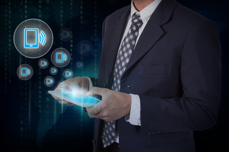 Businessman hand touch screen smartphone icons on a tablet. internet and technology concept.の写真素材
