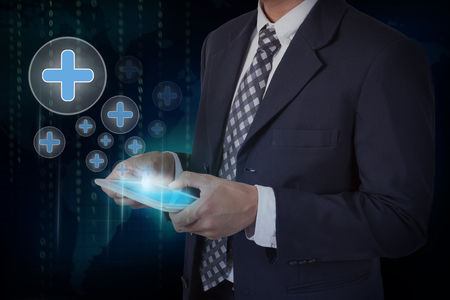 Businessman hand touch screen plus icons on a tablet.の写真素材