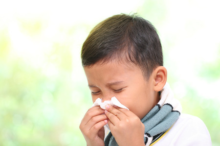 Little boy blowing his nose into tissue. healthcare and medical concept.の写真素材
