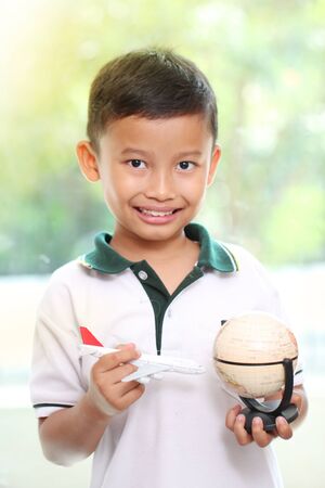 Little boy playing airplane with a globeの写真素材