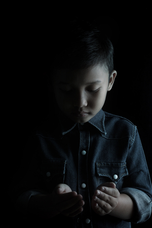 Little boy praying and praising God, isolated on black.の写真素材