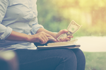 Business woman using calculator counting money and making notes at home office.の写真素材