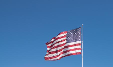 American flag flying against blue skyの写真素材