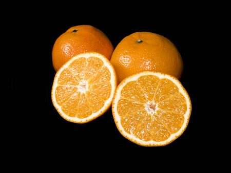 Two oranges and half cut oranges on a black backgroundの写真素材