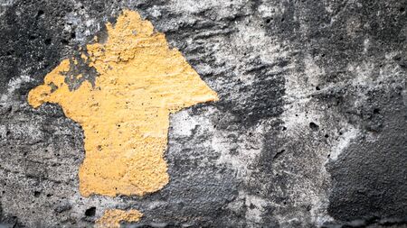 Cement wall with black spots and a yellow arrow pointing upの写真素材
