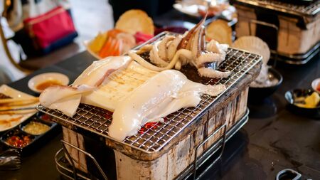 Grilled squid on charcoal grillの写真素材