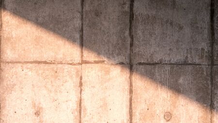 The cement wall with the sunlight shining down diagonally, cutting in half of the pictureの写真素材