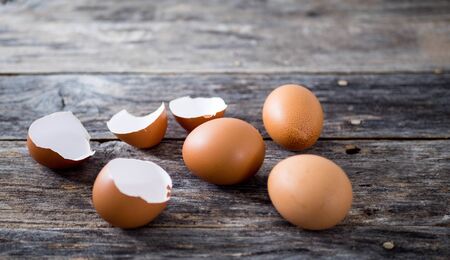 Eggshell and 3 eggs laid on old wooden plates With light shining on the left side