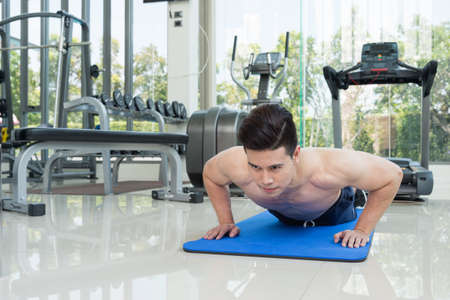 handsome man fitness exercising by doing push ups as part of bodybuilding training in the fitness center or gym, sport and health concept.の写真素材