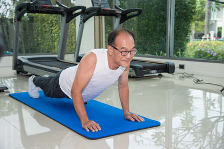 senior man fitness exercising by doing push ups in the fitness center or gym, sport and health...